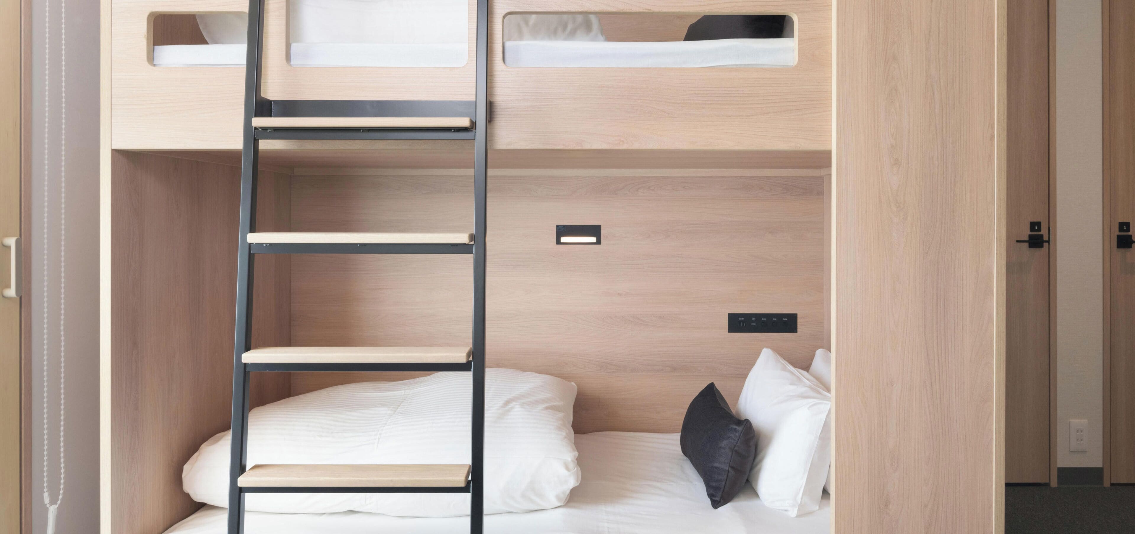 A bunk bed with a ladder, a bedside table, and a power outlet.