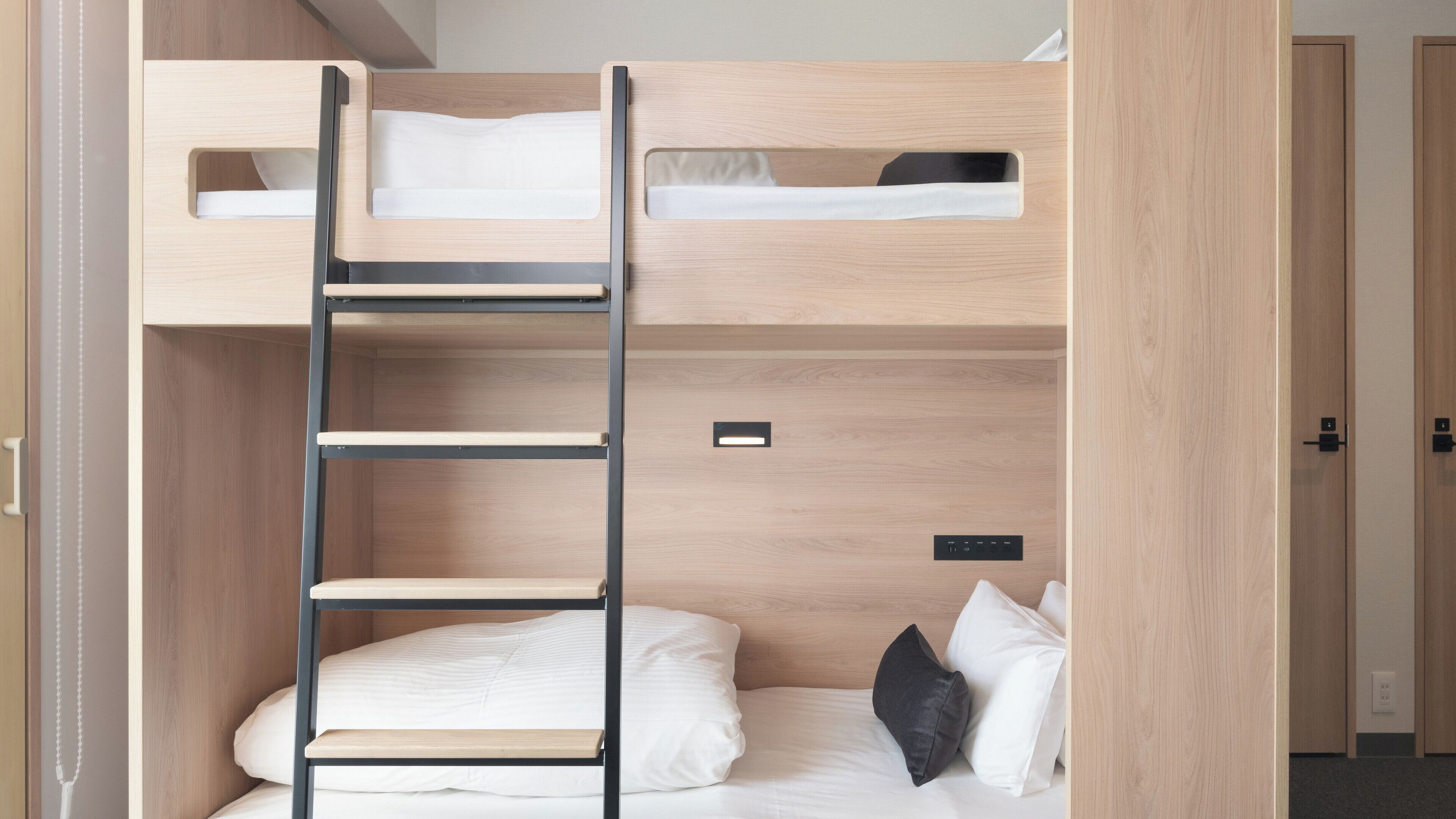 A bunk bed with a ladder, a bedside table, and a power outlet.