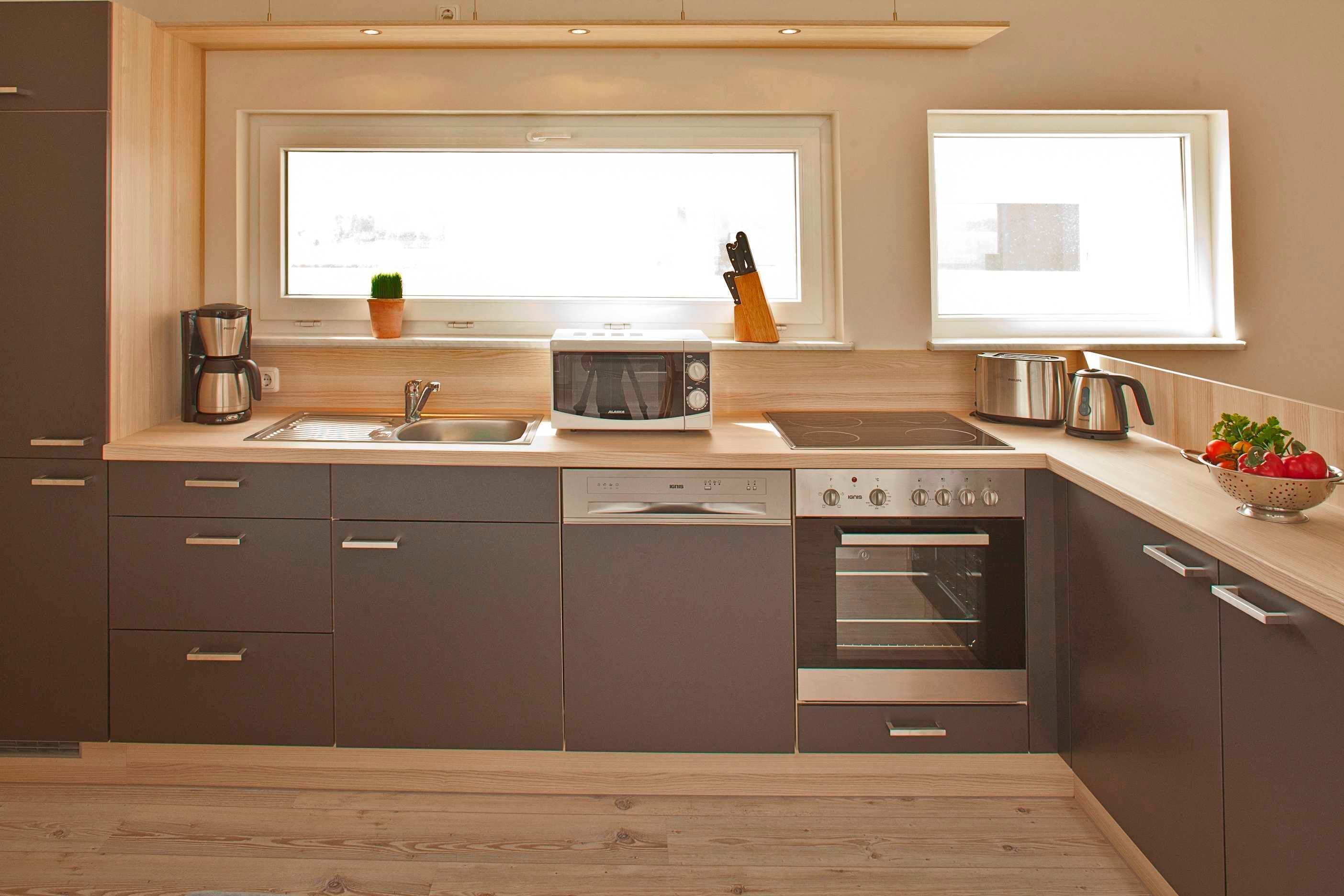 Eine moderne Küche mit Geschirrspüler, Backofen und Kaffeemaschine.