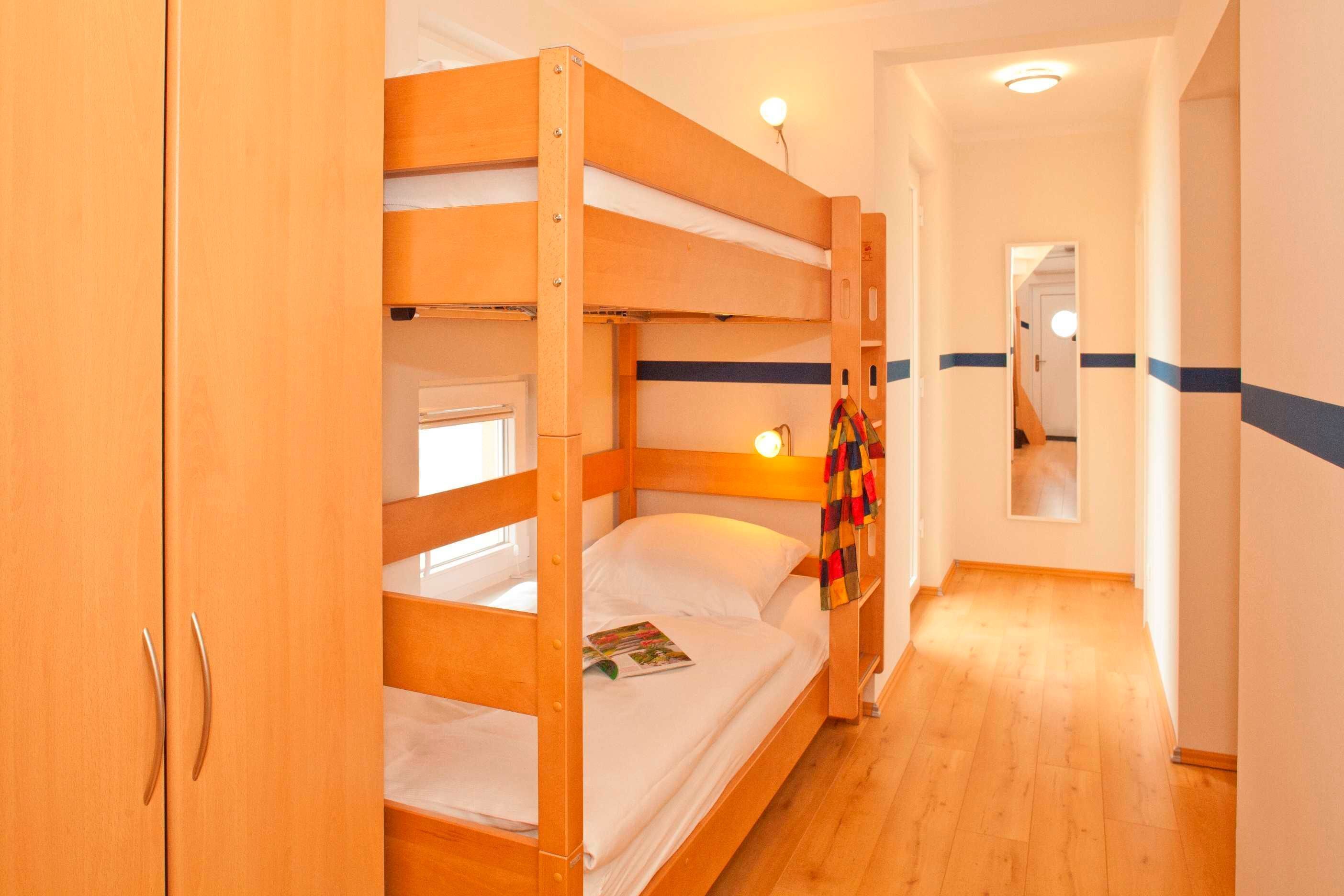 A bunk bed room with wooden walls and a wooden floor.