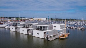Un port de plaisance doté de plusieurs structures flottantes modernes à plusieurs niveaux, qui servent probablement d’entrepôts pour bateaux ou d’ateliers d’entretien.