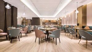 Un restaurante moderno con zona de comedor central, mesas y sillas redondas, además de reservados y una barra.