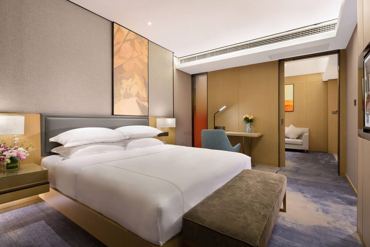 Una habitación de hotel moderna con una cama grande, un escritorio, una silla y un pequeño sofá.