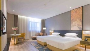Habitación de hotel con dos camas, una mesita, una silla y un escritorio con lámpara.