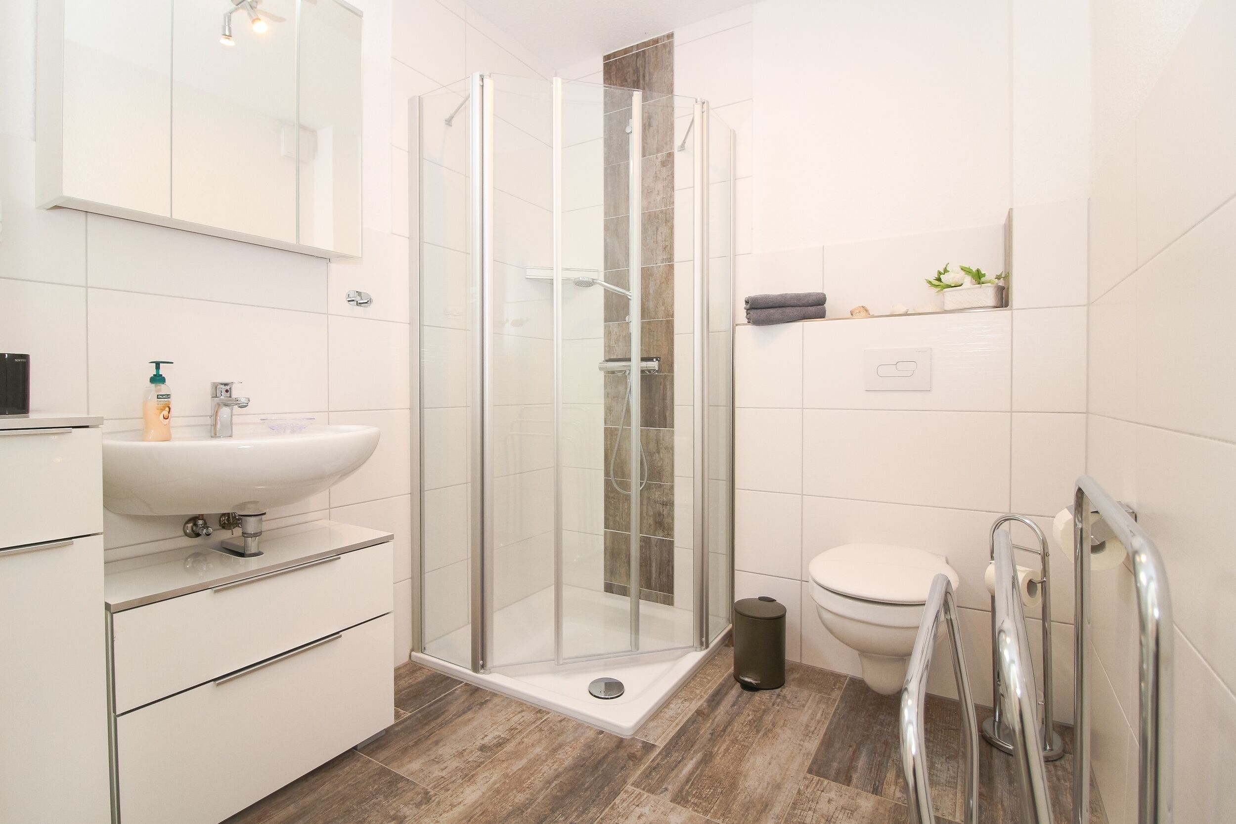 A modern bathroom with a glass-enclosed shower, a white sink, and a toilet.