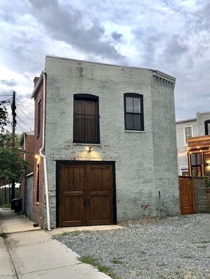 Un bâtiment à deux étages, doté d’une grande porte de garage et d’une petite fenêtre au deuxième étage.