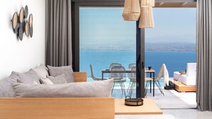 Uma sala de estar moderna com sofá, área de jantar com cadeiras, mesa e vista para o mar.