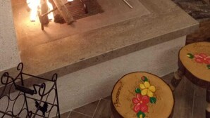 Ein Kamin mit Backsteinverkleidung, ein Sims mit zwei Glasflaschen und ein kleiner Tisch mit floralem Dekor.