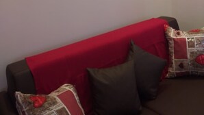 Ein Wohnzimmer mit einem roten Sofa, zwei Bildern von Hirschen an der Wand und einem Bild mit der Silhouette eines Elchs.