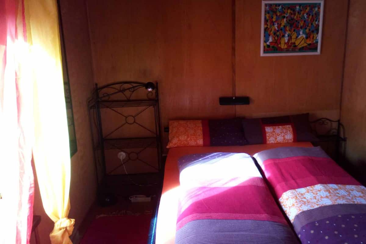 A bedroom with a bed, a metal headboard, and a painting on the wall.