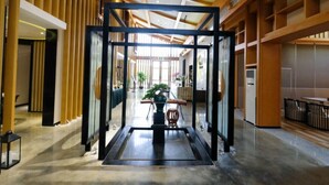 A modern interior with a central glass partition, wooden paneling, and a polished floor. - Manor Landscape Hotel Shenzhen (Shenzhen)