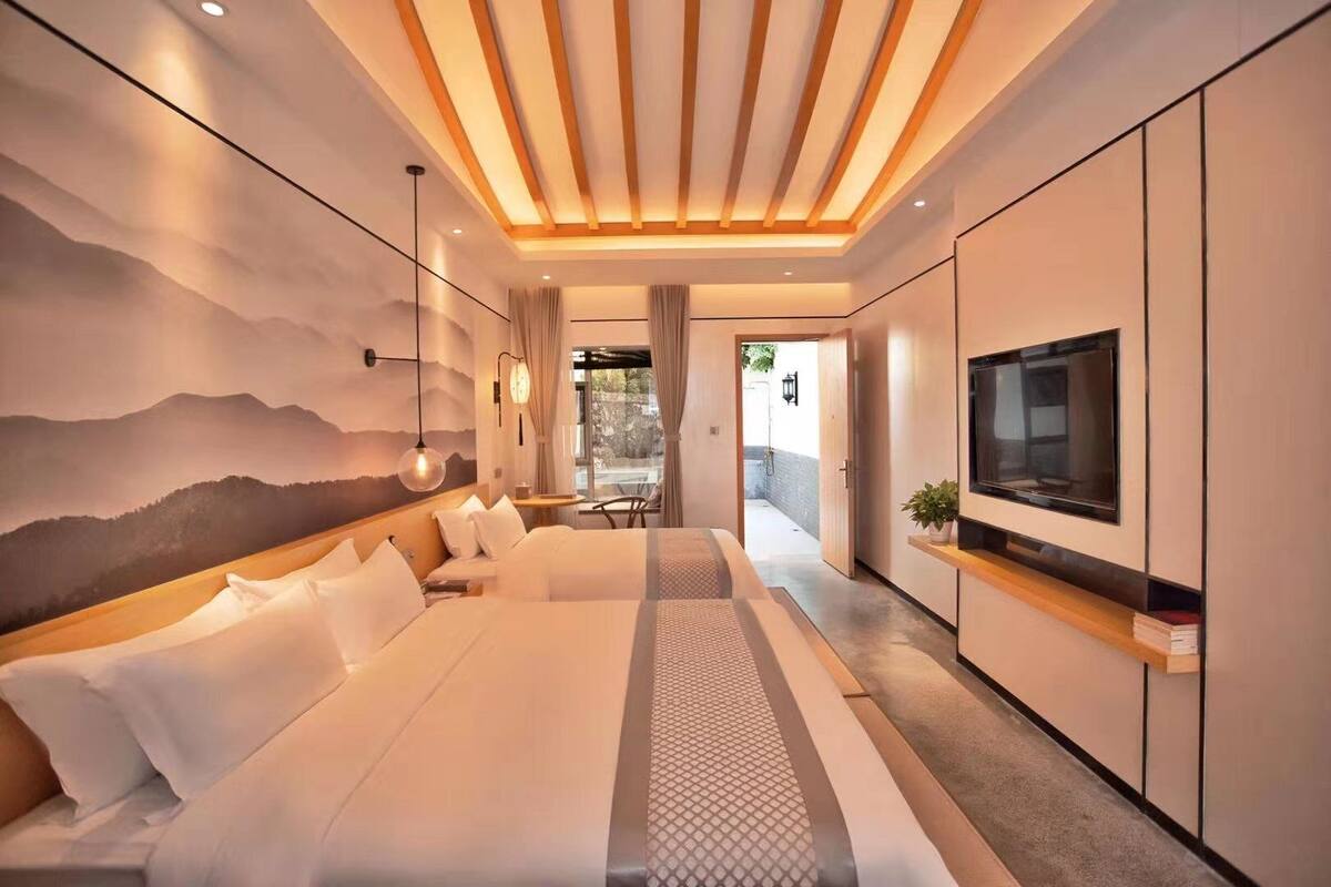 Un hotel moderno con una cama grande, un televisor y un mural de montañas en la pared.