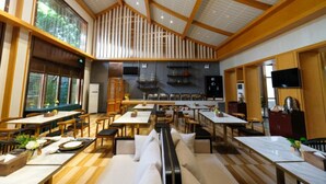 A spacious restaurant with high ceilings, wooden beams, and large windows. Tables and chairs are arranged for dining. - Manor Landscape Hotel Shenzhen (Shenzhen)