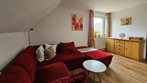 Una sala de estar moderna con un sofá rojo, una mesita blanca pequeña y un mueble de madera.