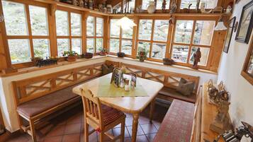 Un rincón acogedor con un banco de madera, una mesa con mantel individual y vistas a través de amplias ventanas.