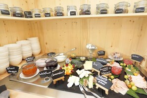 A food display with various cheeses, fruits, and condiments.