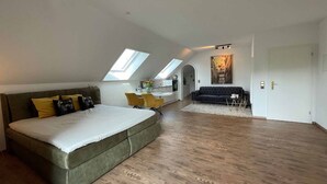 Ein geräumiges Schlafzimmer im Loft-Stil mit großem Bett, einer Couch und einem Essbereich.