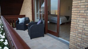 Ein Balkon mit Korbmöbeln und einer Schiebetür, die in ein Schlafzimmer führt.