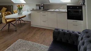 Ein modernes Loft-Apartment mit Küche, Essbereich und Wohnbereich. Es verfügt über Dachfenster, eine Couch und einen Couchtisch.