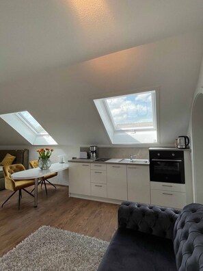 Cozy living space with a loft-style design, featuring a kitchenette, dining area, and comfortable seating.