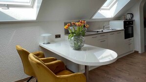 Eine moderne Küche mit Oberlichtern, einer weißen Arbeitsplatte und gelben Stühlen.