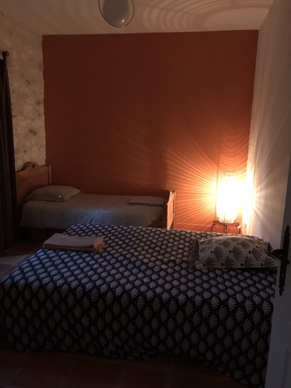 A bedroom with a bed, a bedside table, and a lamp.