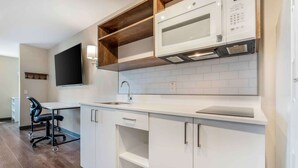 A modern kitchen with white cabinetry, a microwave, and a flat-screen TV mounted above the counter. - Extended Stay America Premier Suites Ukiah (Ukiah)