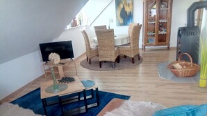 Una sala de estar acogedora con un sofá, una mesa de centro y un comedor con sillas de mimbre.
