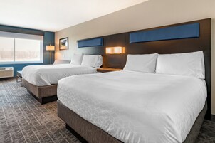 Habitación de hotel con dos camas, un ventanal grande, una lámpara de pared y un aire acondicionado de pared.