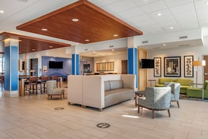 En moderne lobby med siddeområde, fjernsyn og receptionsdisk.