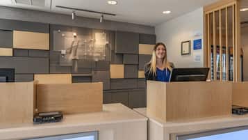 Welcome to our reception area, where guests can check in and enjoy a modern design featuring a flat-screen monitor and a unique geometric pattern wall.