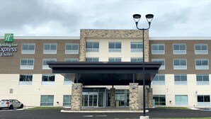A Holiday Inn Express & Suites building with a modern design, featuring a stone facade and a covered entrance.