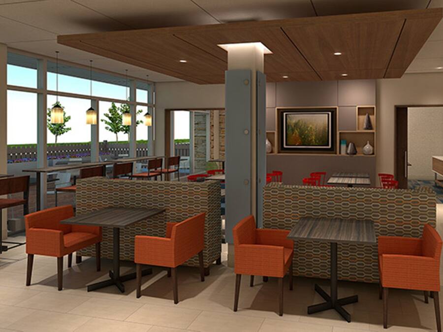 A modern restaurant with high tables and orange chairs, a bar area, and a large window with a view.