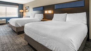 Habitación de hotel con dos camas, un ventanal grande y una lámpara de pared.