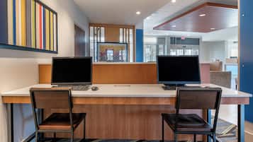 A workspace with two desks, each with a laptop and a keyboard, two chairs, and a patterned carpet.