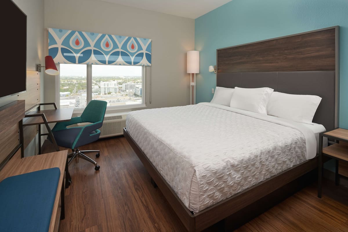 A modern hotel room with a large bed, a desk, and a chair.
