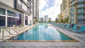A swimming pool with lounge chairs, surrounded by modern buildings with balconies. - Tru by Hilton Fort Lauderdale Downtown (Fort Lauderdale)