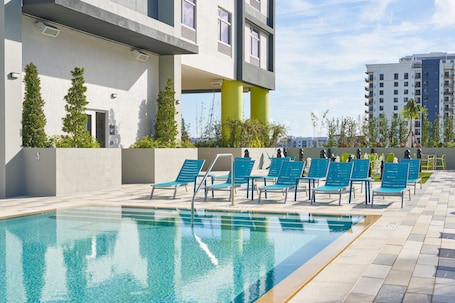 Una piscina al aire libre, sillones reclinables de piscina
