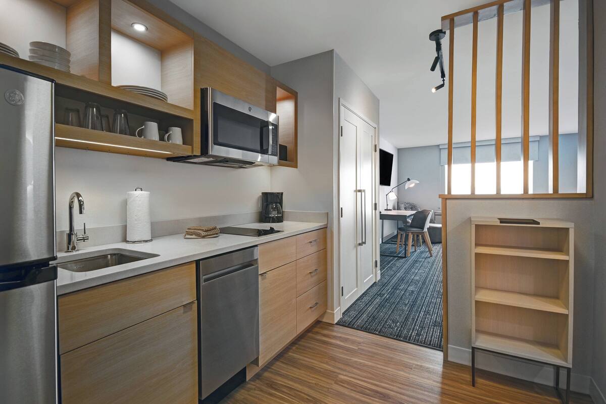 A modern kitchen with stainless steel appliances, wooden cabinets, and a built-in microwave.