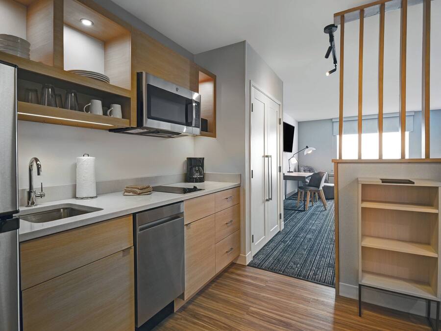 A modern kitchen with stainless steel appliances, wooden cabinets, and a built-in microwave.