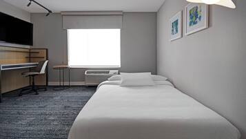 Une chambre d’hôtel équipée d’un lit, d’un bureau, d’une chaise, d’une télévision et d’une fenêtre donnant sur un paysage agréable.
