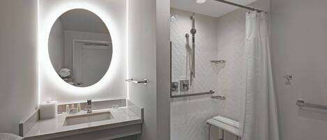 A modern bathroom with a round mirror, a sink, and a shower area.