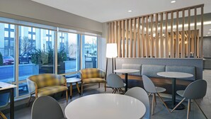 Un interior moderno con arreglos de asientos, ventanas amplias y un separador decorativo.