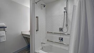 Un baño moderno con ducha de vidrio, bañera y tocador con toallero.