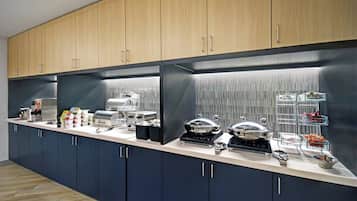 Una cocina moderna con armarios azul oscuro, un refrigerador de acero inoxidable y diversos electrodomésticos como una cafetera y un tostador.