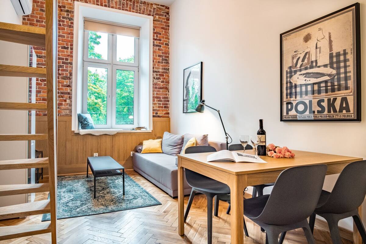 Une pièce chaleureuse avec une table en bois, un banc, un canapé et une fenêtre donnant sur un paysage verdoyant.