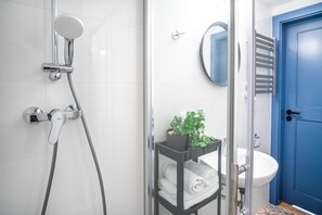 A modern bathroom with a shower, a sink, and a blue door.