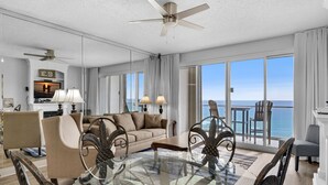 A spacious living room with a large glass table, a sofa, and a ceiling fan. - 🌅 Stunning Beach Front- Sterling Sands 707 🏝️ (Destin)