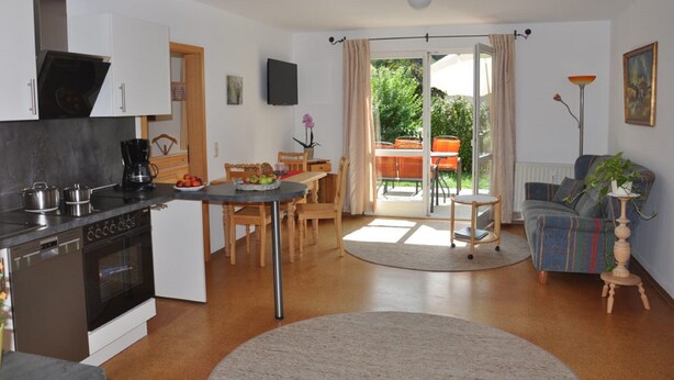A modern kitchen with a built-in oven and a dining area with a table and chairs. - Ferienwohnung Gäste Oase (Bad Windsheim)