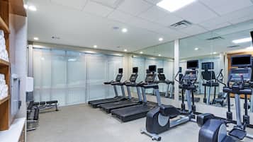 A modern gym with treadmills, weight machines, and a mirrored wall.